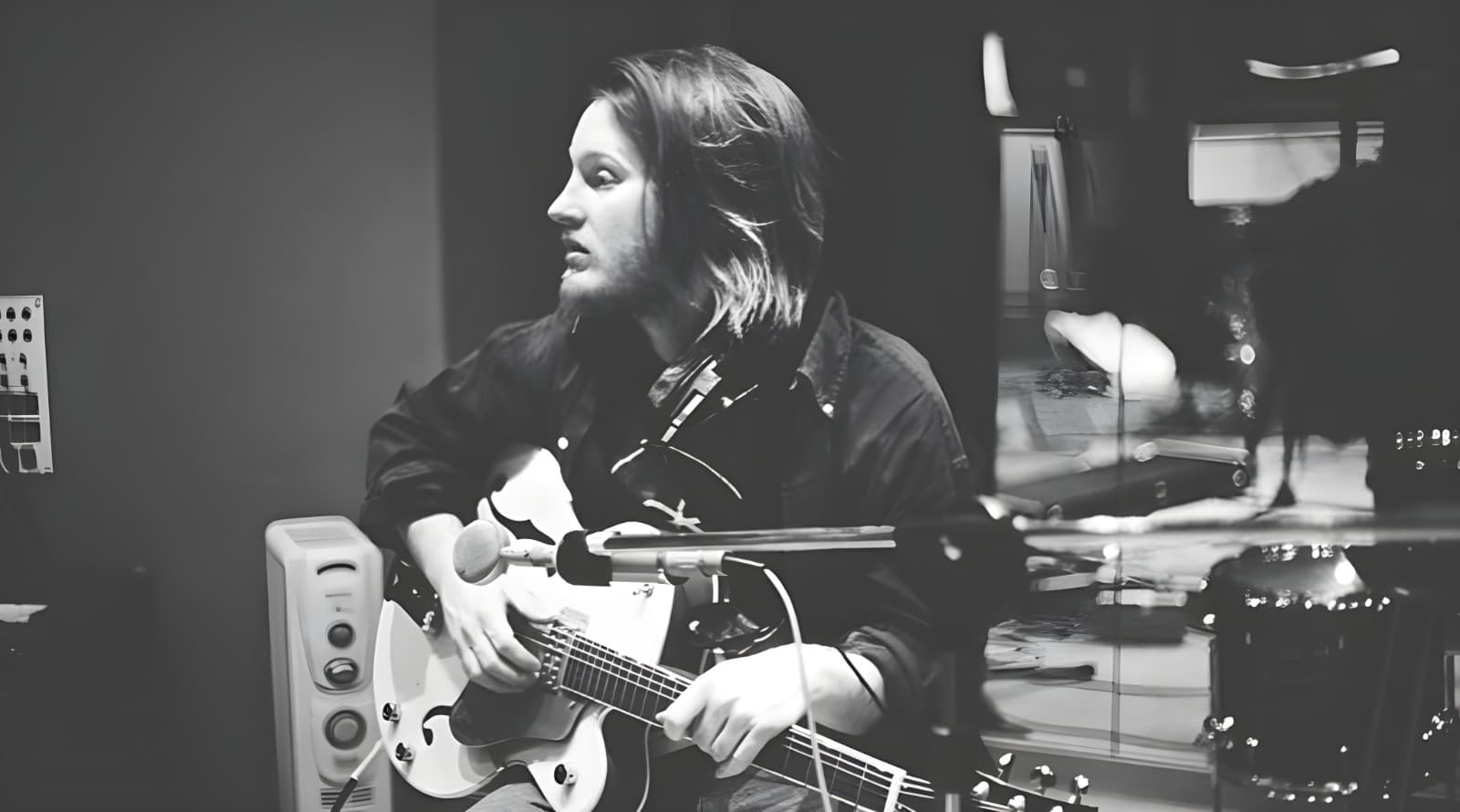 Studio recording session with a hollow-body guitar at the microphone