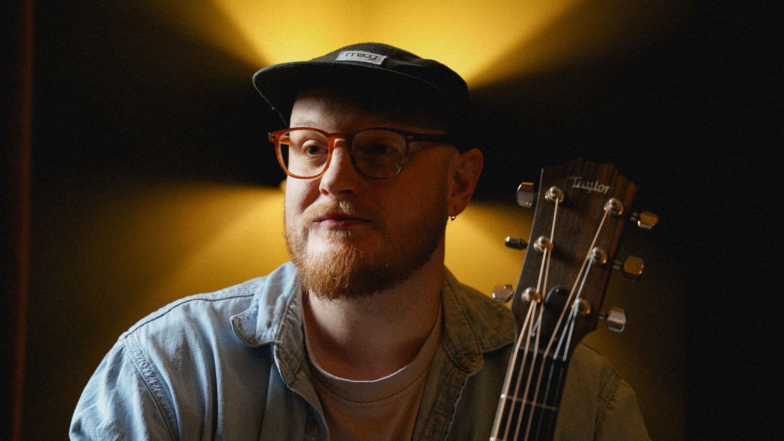 Chris Hall with a Taylor acoustic in warm directional light